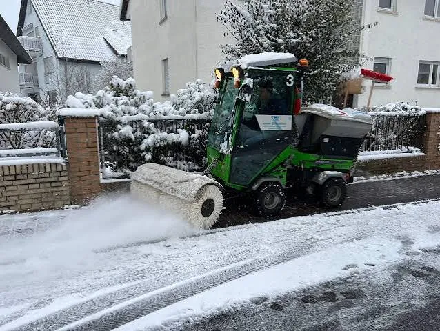 Räumfahrzeug räumt und kehrt eine verschneite Straße frei